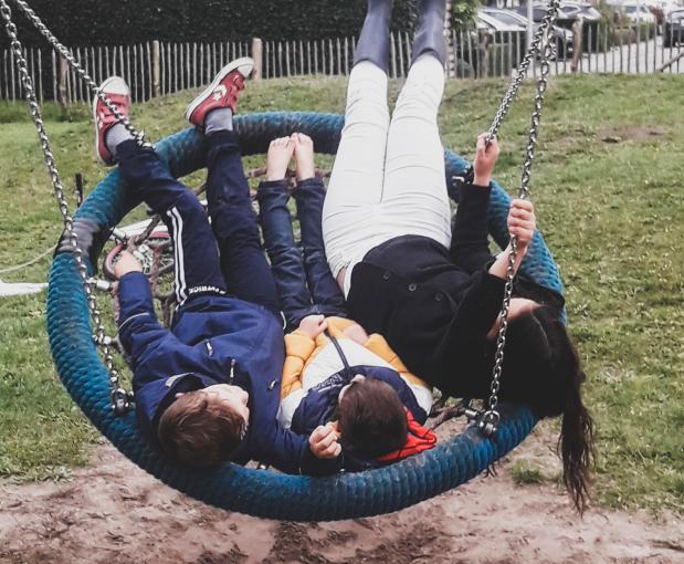 Drie kinderen die samen in een speeltuin aan het spelen zijn.