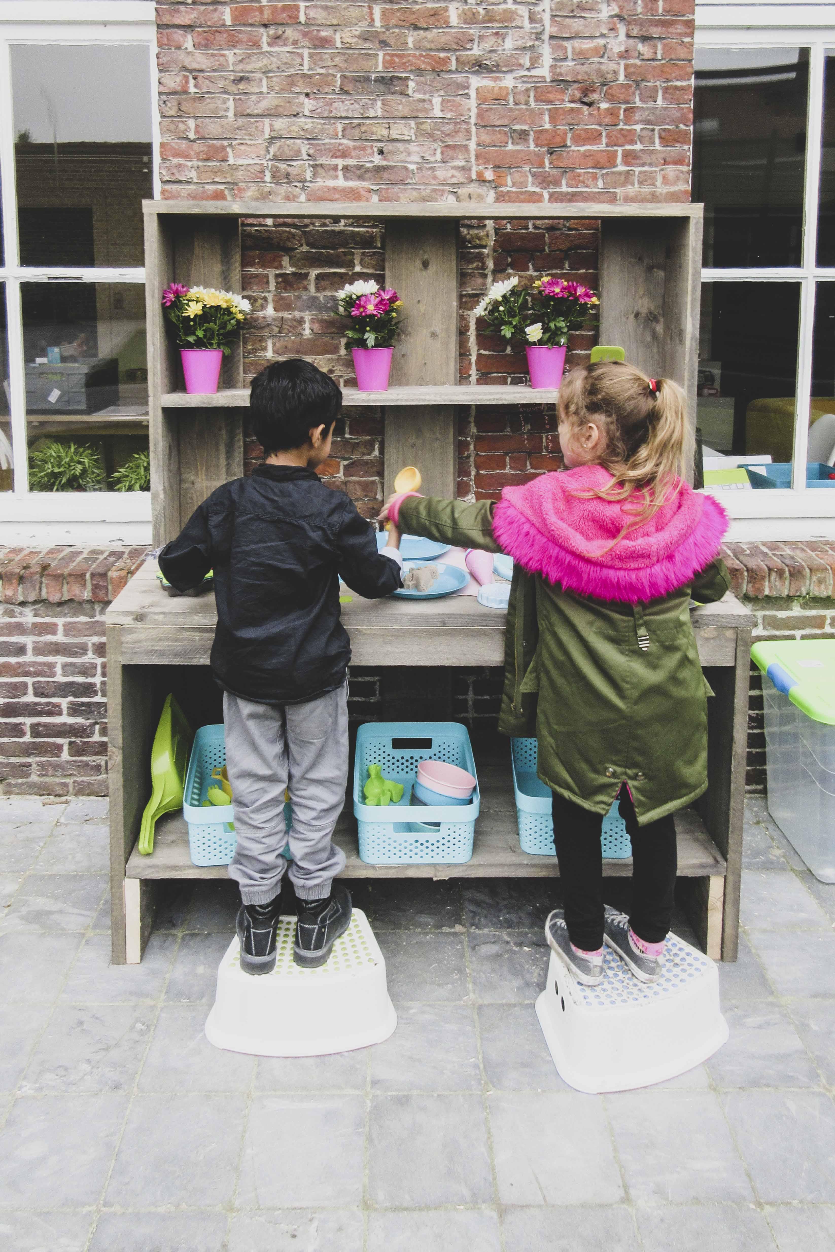 Twee kindjes die samen met zand aan het spelen zijn.